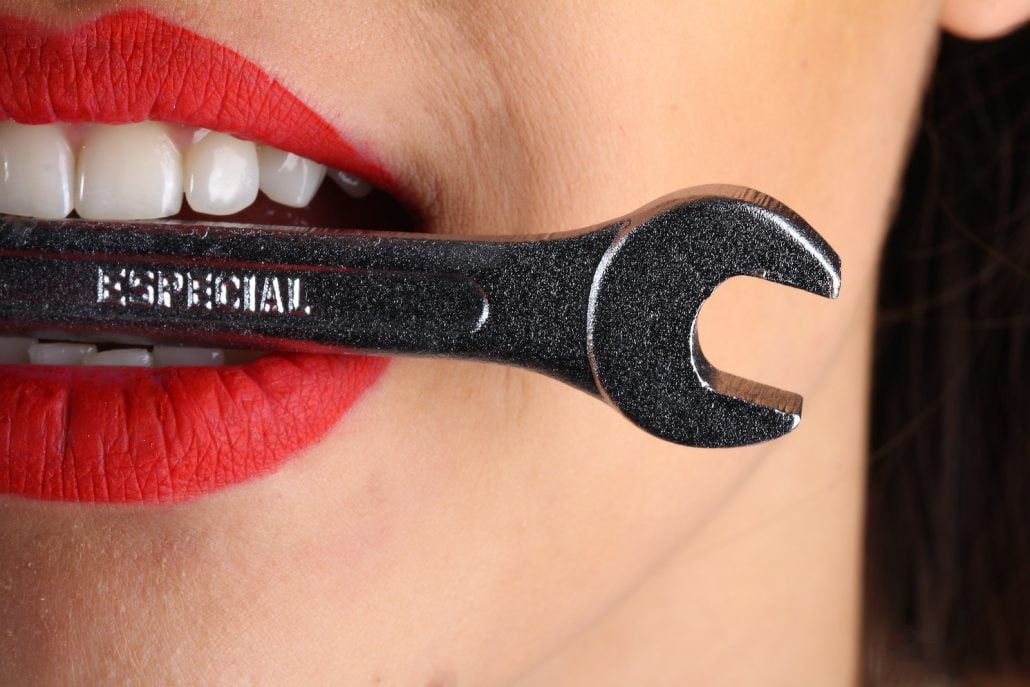 Photo by Rodolfo Clix Close View of Woman With Red Lips Biting Gray Special Wrench